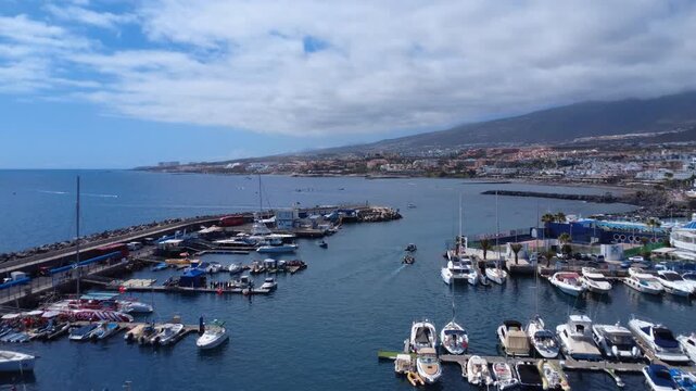 Vista a&eacute;rea amplia de un puerto deportivo con barcos amarrados, la localidad tur&iacute;stica de Costa Adeje y monta&ntilde;as volc&aacute;nicas bajo las nubes, Tenerife, Espa&ntilde;a