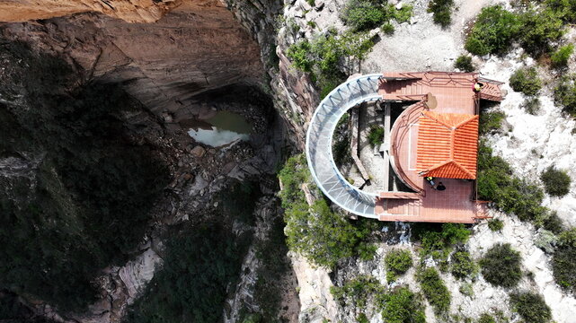 Aerial view of El Vergel canyon with its dramatic rock walls, a small pool of water at the base, and the observation deck with a red-tiled roof in Torotoro, Potosi Department, Bolivia.