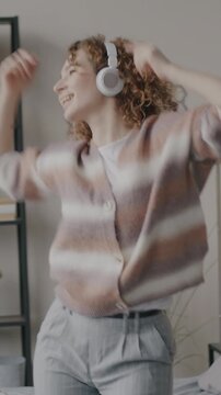 Slow motion of carefree young woman dancing to music relaxing in apartment in leisure time. Modern youth culture and entertainment at home concept.