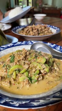 Stir-fried Thai spicy curry with minced fish paste and Adenia viridiflora fruits, served in a bowl. Traditional authentic local northeastern Thailand food.