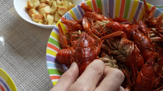 4K footage of hand taking boiled red crayfish from a plate, beer snacks for game day