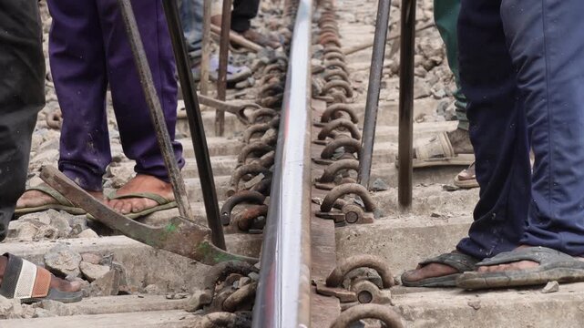 Railway workers performing track maintenance and adjustment