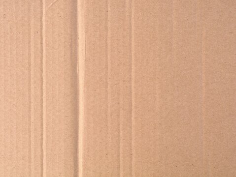 Close up of a brown folded corrugated cardboard sheet with creases and lines. Perfect for shipping, packaging concepts, sustainable design backgrounds, and recycling themes