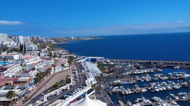 Paneo a&eacute;reo sobre edificios tur&iacute;sticos blancos y un puerto deportivo lleno de barcos en la costa atl&aacute;ntica de Costa Adeje, Tenerife