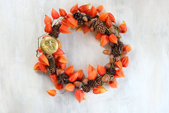Autumnal wreath made of natural materials on light background. Cozy home handmade decor from physalis, cones, acorns and moon amulet. DIY crafts, ideas for fall season interior decoration. flat lay