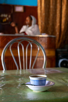 Coffee cup on a table with woman in background, Massawa, Eritrea