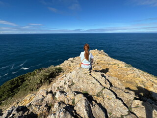Woman overlooking the Atlantic Ocean from rocky coast in Algarve, Portugal © Alex