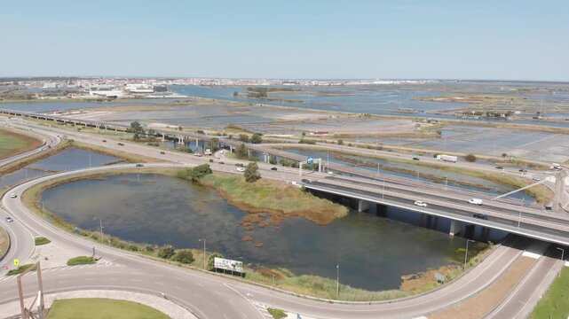 Aerial drone pan over salt pans and a busy road.