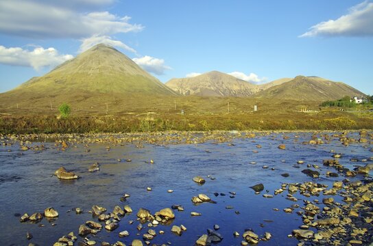Landscape with mountains in the background, a shallow river full of stones and a clear blue sky with some clouds, Slicgachan, Isle of Skye, Scotland, United Kingdom