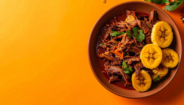 Top Down View of Venezuelan Pabellon Criollo Shredded Beef with Fried Plantain Slices in Terracotta Bowl on Vibrant Orange Background