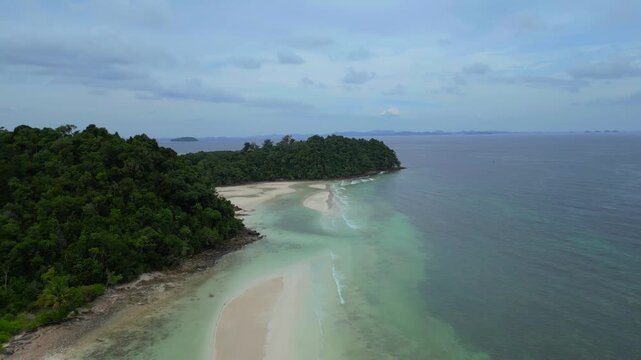 Aerial view of the sandy coastline and turquoise waters of Batam Island surrounded by lush tropical forest in Batam, Riau Islands, Indonesia.