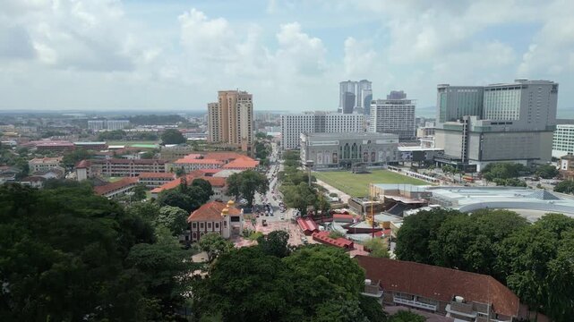 Aerial view of the cityscape of Malacca featuring modern buildings, historic architecture, and lush green trees under a bright sky in Malacca, Malacca, Malaysia.
