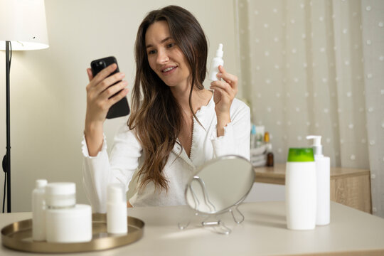 Woman filming a beauty blog about skincare products and cosmetics during a home beauty routine