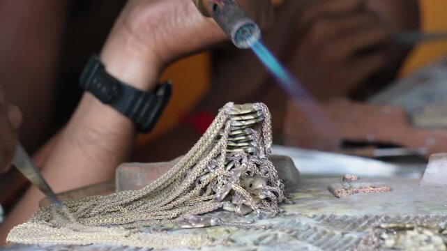 Goldsmith using gas torch to solder fine silver chain jewelry