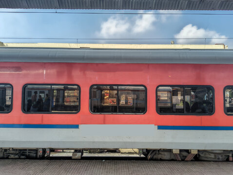 Passenger train coach standing at railway station platform under blue sky