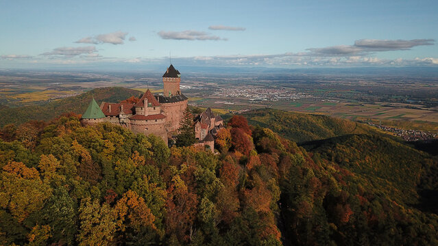 Aerial view of Chateau du Haut-Koenigsbourg surrounded by autumn forests on a hillside with a distant valley landscape in Orschwiller, Grand Est, France.