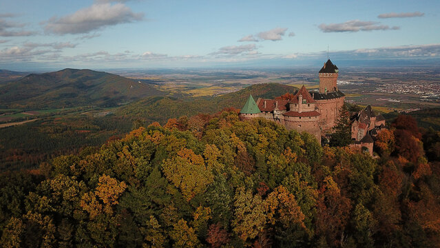 Aerial view of the historic Chateau du Haut-Koenigsbourg surrounded by a dense autumn forest with vibrant fall foliage in the Vosges mountains in Orschwiller, Grand Est, France.