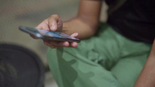Closeup of male hands holding mobile phone and scrolling through social media feed or content. Concept of doom scrolling, internet browsing, texting, or digital device usage.