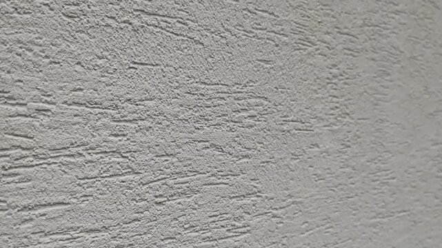 Grey plaster texture wall surface panning left smoothly, showcasing rough decorative facade rendering for architectural background and modern interior design visuals.
