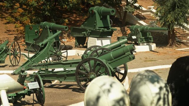 Obsolete, abandoned, and rusty combat guns stand amidst the natural landscape. A graveyard of weaponry. An echo of war.