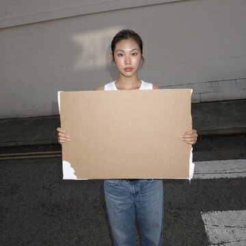 Urban portrait of a girl holding a torn cardboard for copy space