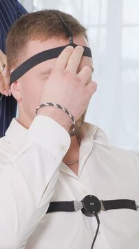Man undergoing a polygraph examination as a polygraphist attaches sensors to his head and chest, preparing him for the questioning and monitoring of his physiological responses