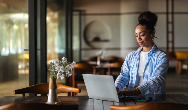 Successful black woman working remotely on her laptop in a stylish cafe