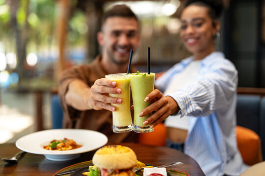 Multiethnic couple enjoying a joyful dining experience by the beach. Great food, perfect summer vibe