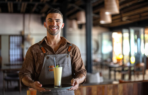Waiter with smoothies on a tray in a stylish eatery offering friendly service and a cozy vibe