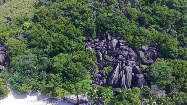 Aerial view of lush tropical forest and large granite rock formations at Anse Reunion, La Digue, Seychelles.