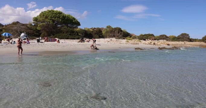 Vista della spiaggia dell'Oasi Biderosa, a Orosei (Sardegna, Italia), con persone che si rilassano sulla sabbia bianca e acque turchesi e cristalline.