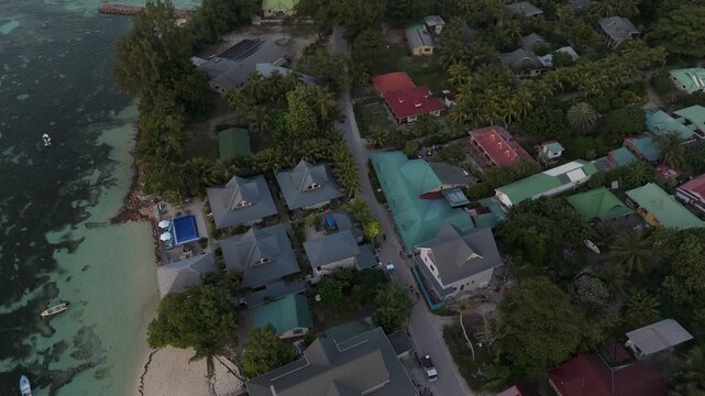 Aerial view of Anse Reunion with tropical houses, lush palm trees, and turquoise waters along the coastline in Anse Reunion, La Digue, Seychelles.