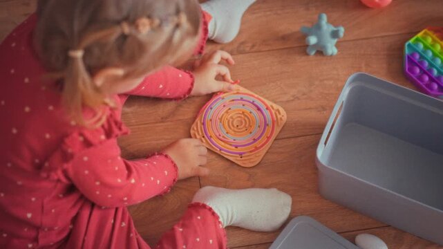 Child sits on the floor, intently playing as they connect bright toys of different shapes. This simple play nurtures early development, boosting problem-solving skills and imagination in cozy setting