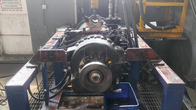 Heavy transmission unit mounted on test bench during workshop testing.