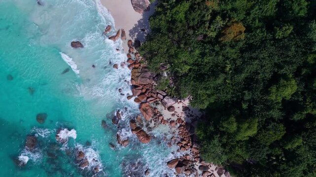 Aerial view of Anse Lazio beach with turquoise water, white sand, and granite boulders surrounded by lush tropical forest in Baie Sainte Anne, Seychelles.