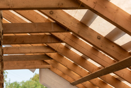 Wooden roof rafters and beams forming the framed structure of a new residential house, showcasing carpentry, timber framing and the unfinished construction process and craftsmanship