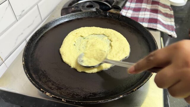 Person preparing indian dosa on a griddle