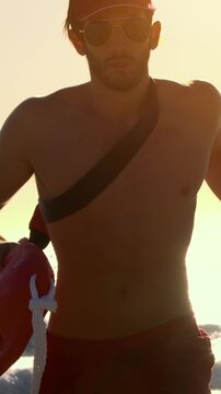 Male lifeguard running along the beach. Vertical video.