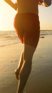Male lifeguard running along the beach. Vertical video.