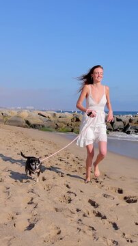 Attractive woman walking on the beach with her dog. Slow Motion.Vertical video.