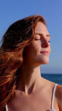 Portrait of an attractive woman at the beach at sunset. Slow Motion. Vertical video.