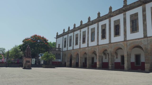 Statue of Fray Antonio de Segovia standing in the central courtyard of Our Lady of Zapopan Basilica with colonial church architecture and clear blue sky in the background