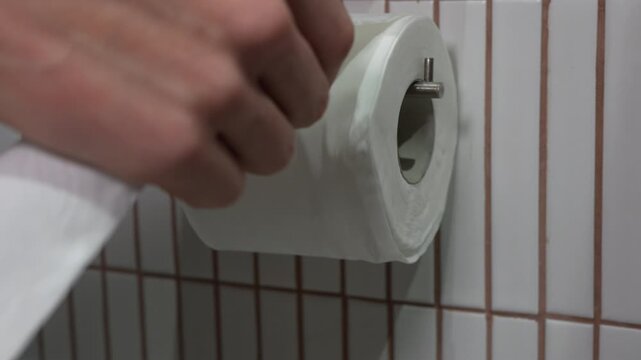 4K close up footage of white soft toilet paper roll with leaf pattern embossing on holder in bathroom