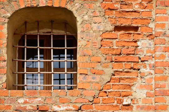 Window with a grate on an aged brick wall