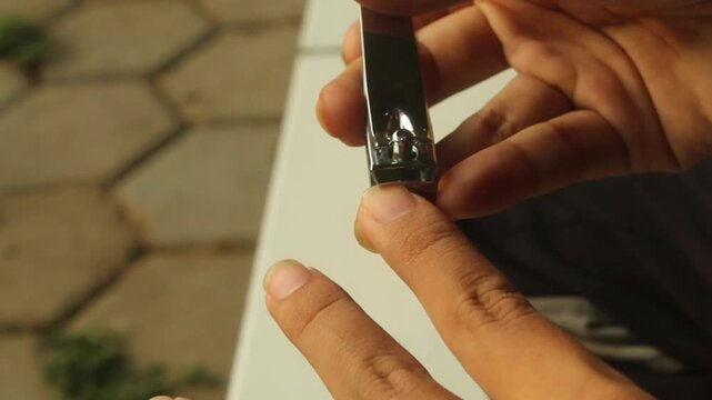 Close-up of a hand trimming fingernails with a stainless steel nail clipper, illustrating personal grooming, nail care, hygiene, self-care, and everyday hand care.