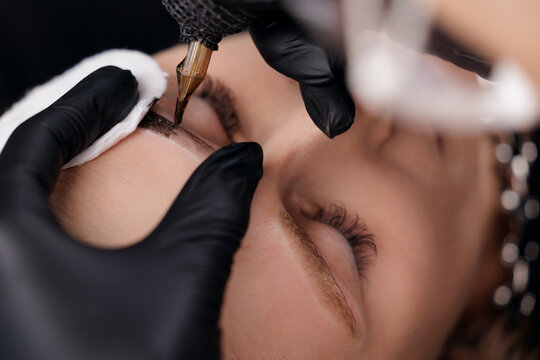 Female eyebrow microblading procedure closeup, top view
