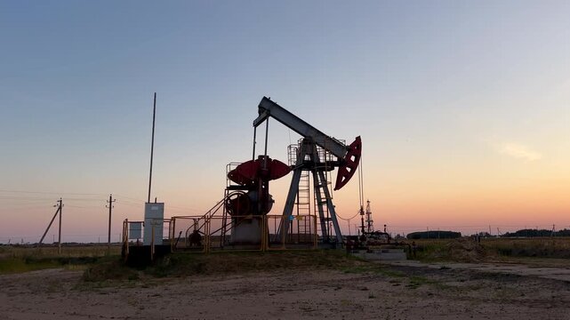 Oil extraction on sunrise. Crude pump jack working on oil field on sunset. Industrial landscape mood. Pumpjack in oil well of oil field on sunrise in Industrial crude area. 