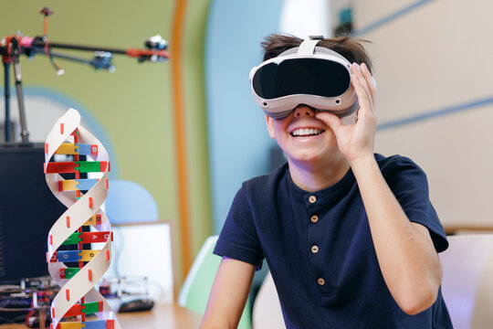 Happy Boy smiling wearing virtual reality headset in classroom
