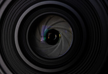 Camera Lens Aperture Blades Macro Close-Up,A detailed macro close-up photograph looking directly into a camera lens, featuring the aperture blades, optical glass, and green anti-reflective coating.  © banjongseal324