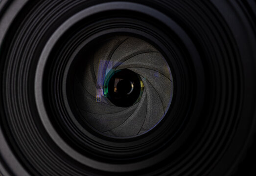 Camera Lens Aperture Blades Macro Close-Up,A detailed macro close-up photograph looking directly into a camera lens, featuring the aperture blades, optical glass, and green anti-reflective coating. 
